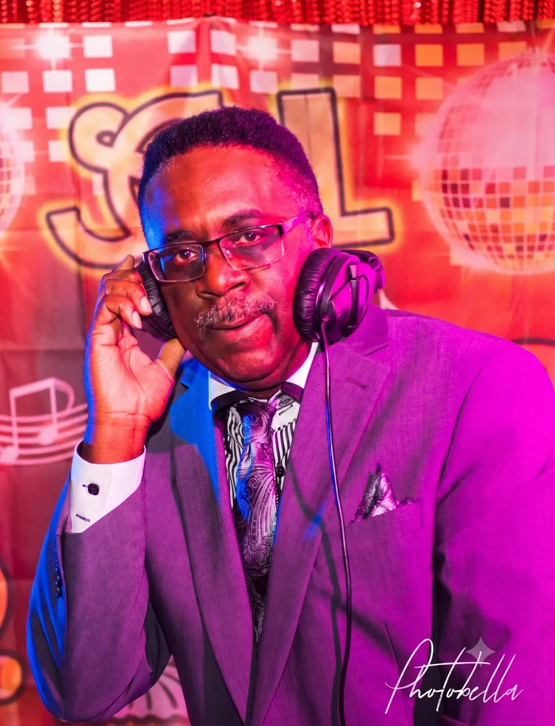 DJ Roy Stone in a purple suit with headphones at a Soul Train themed event